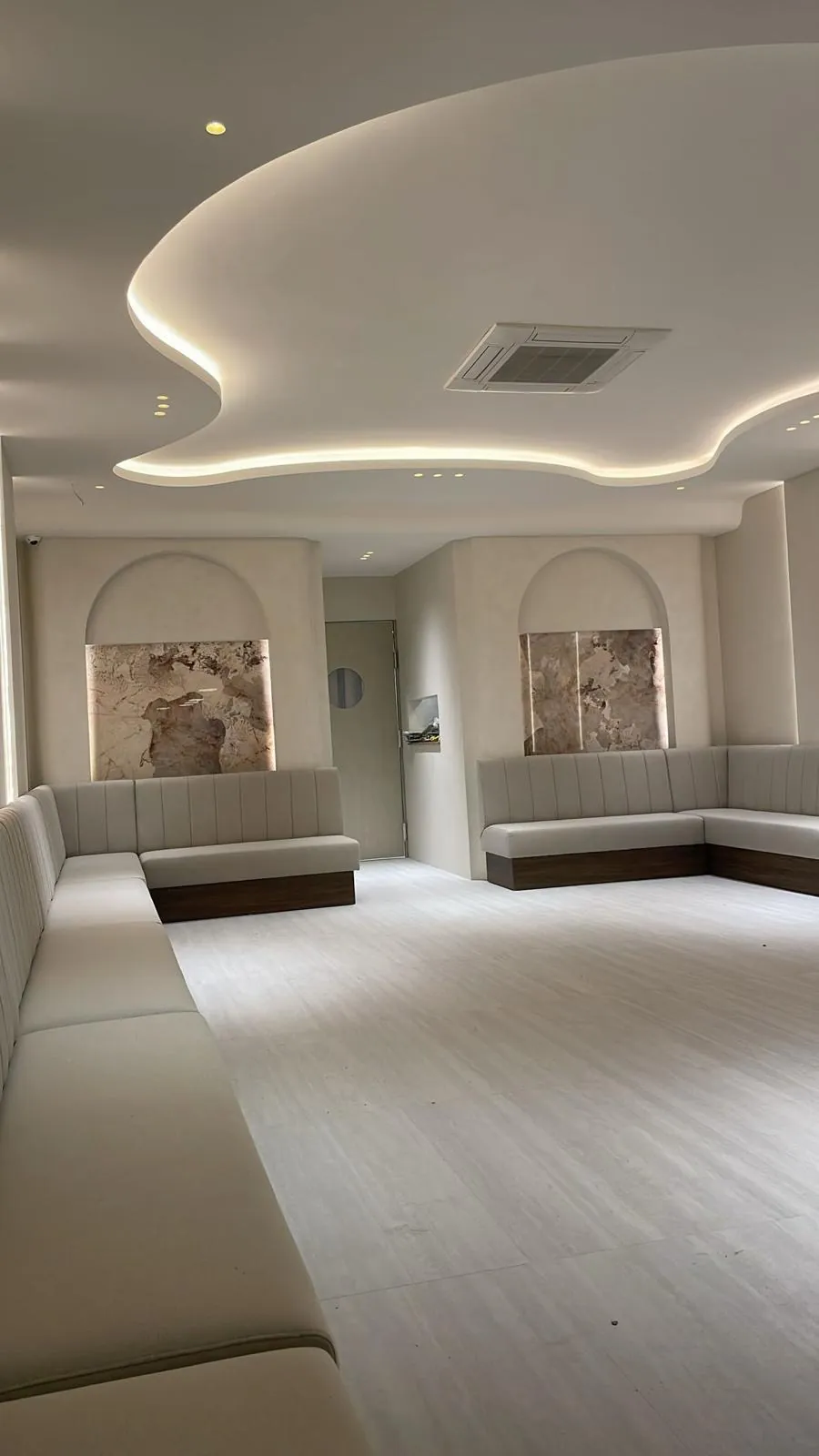 Sala terminada con hornacinas en arco, paneles retroiluminados y techo curvo con iluminación