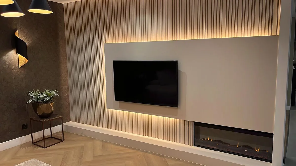 Pared de salón con listones verticales, iluminación indirecta, televisor de pared y chimenea empotrada